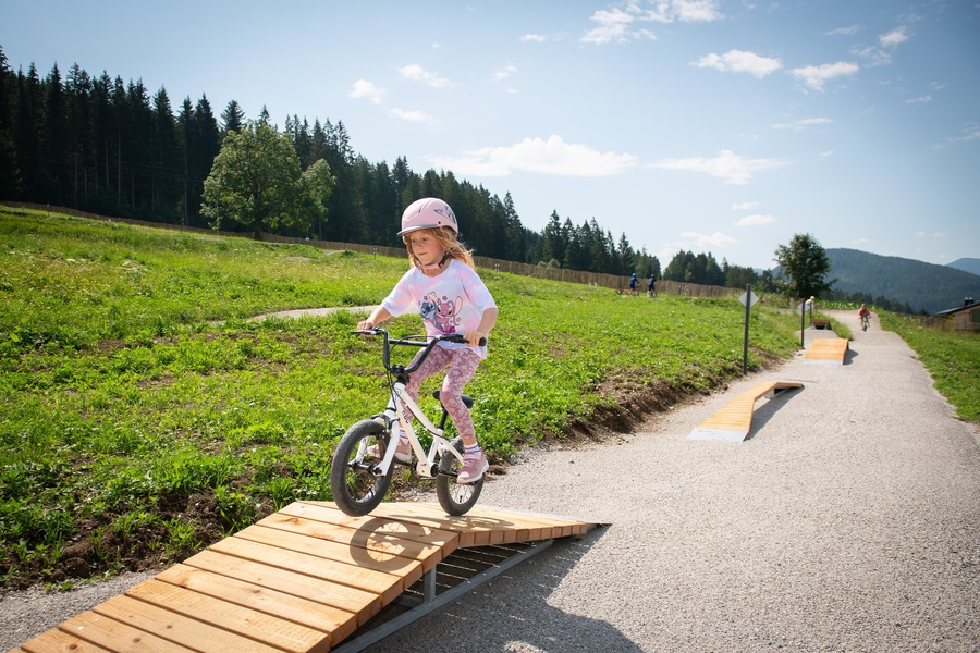 Skills Element im Martinerhof, ©Martinerhof, Michael Gruber Ein Mädchen fährt mit dem Fahrrad über ein kleines Hindernis am Bikepark in St. Martin
