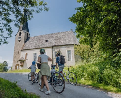 Eine Familie bestehend aus Mann, Frau und 2 kleinen Jungen schiebt ihre Fahrräder zur Kirche am Georgenberg
